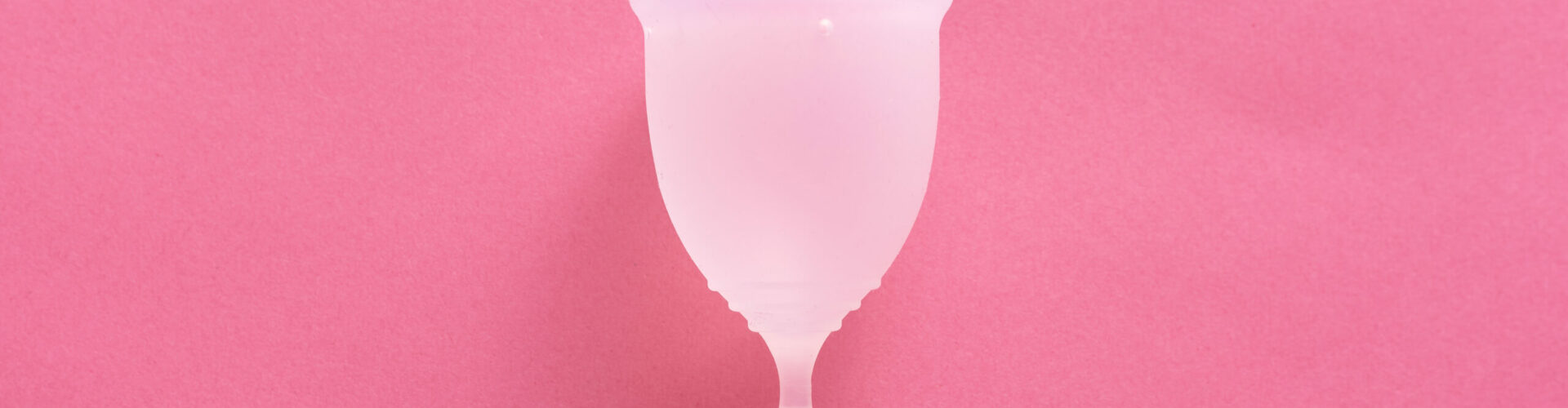 Close up shot of menstrual cup isolated over pink background. Studio picture of modern sanitary products for period. Women health concept, gynecology, hygiene, zero waste alternatives concept.